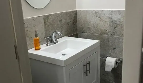 A bathroom with a sink, mirror and toilet paper.