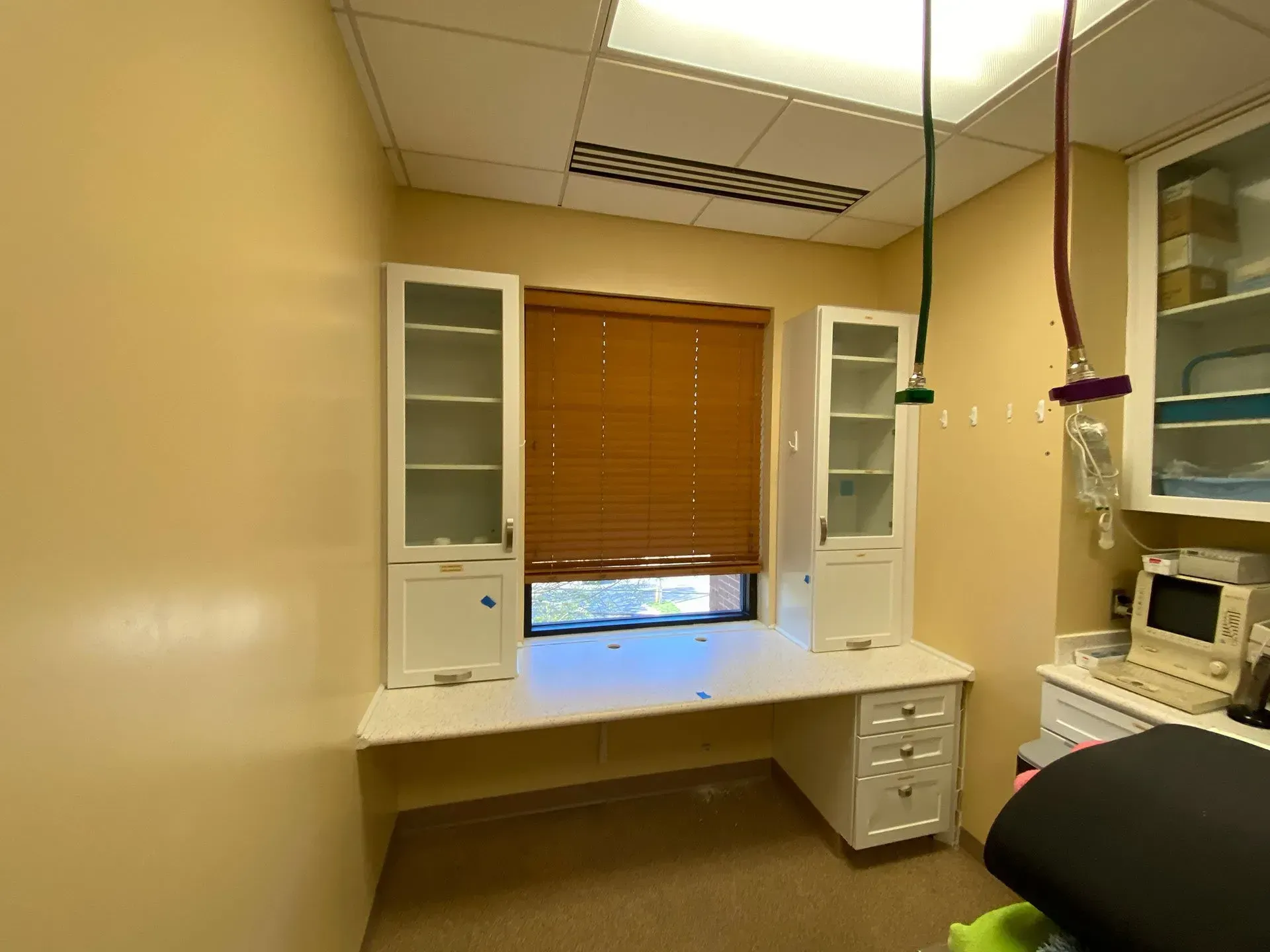 A room with a desk and cabinets and a window.