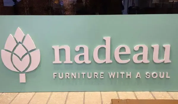 A green sign that says nadeau furniture with a soul.