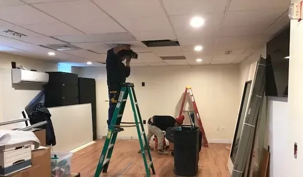 A man is standing on a ladder in a room.