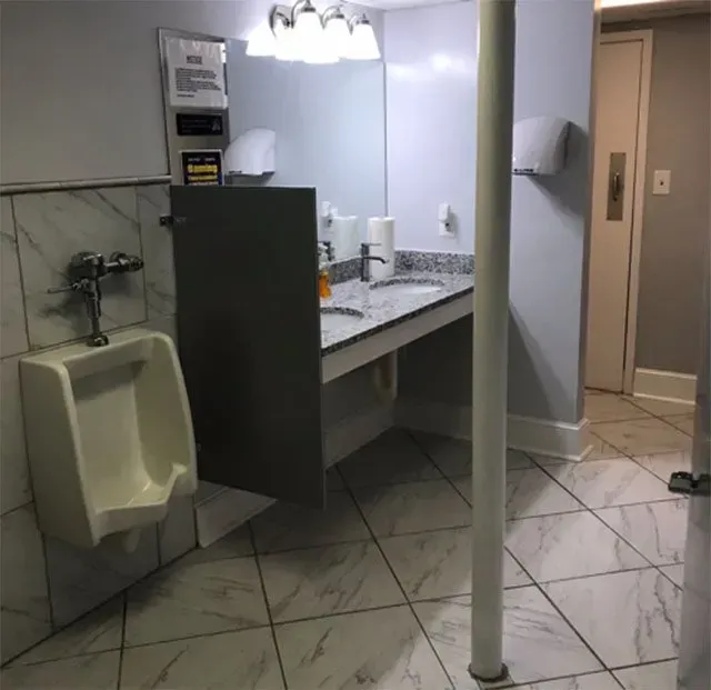 A bathroom with a urinal a sink and a mirror.