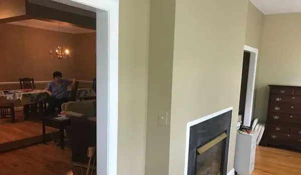 A man is sitting on a couch in a living room next to a fireplace.