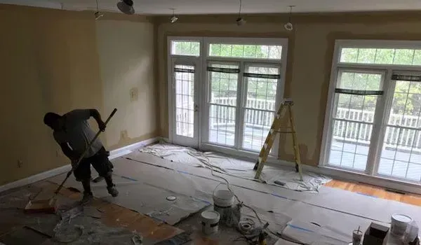 A man is painting a wall in a living room.