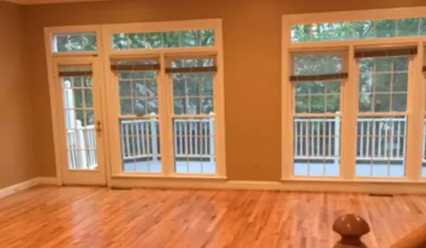 An empty living room with hardwood floors and lots of windows.