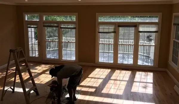 A man is bending over in an empty room with a ladder.