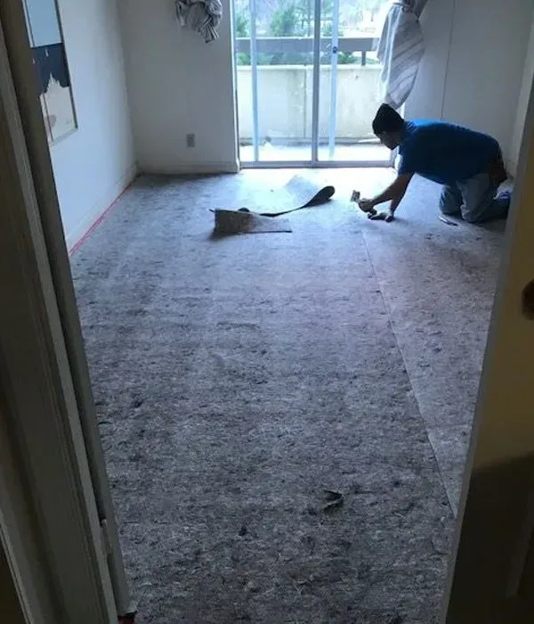 A man is kneeling on a carpeted floor in a room.