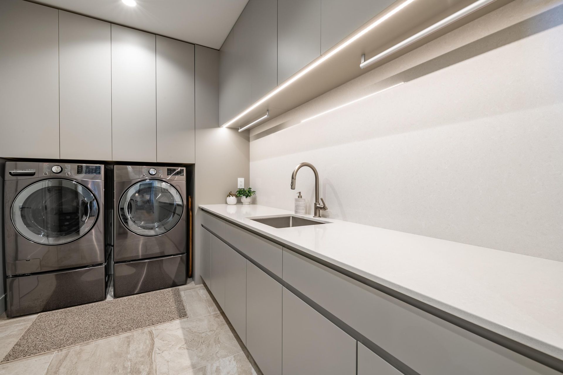 A laundry room with two washers and dryers and a sink.