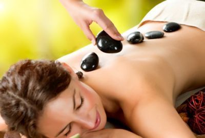 Woman receiving hot stone massage on her back, in a spa setting.