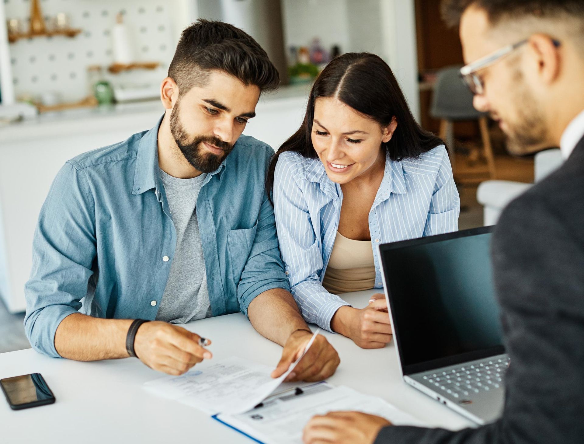 Couple reviewing documents with a financial advisor in a bright, modern home.