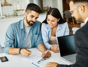 Couple reviewing documents with a financial advisor at a table.