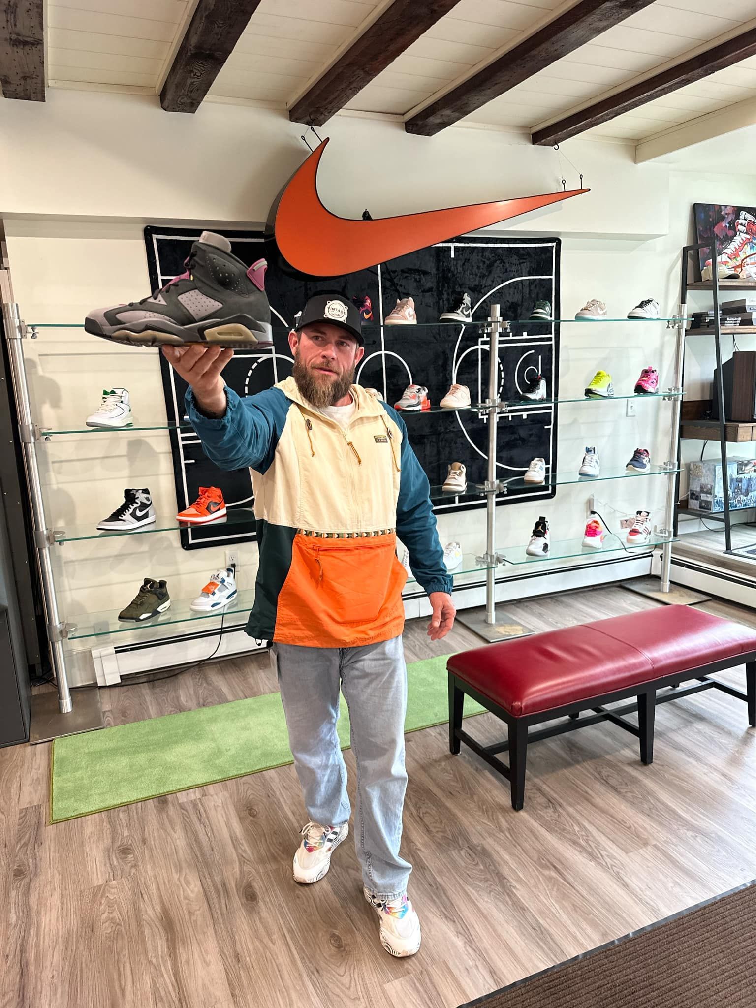 A man is standing in a shoe store holding a pair of shoes.