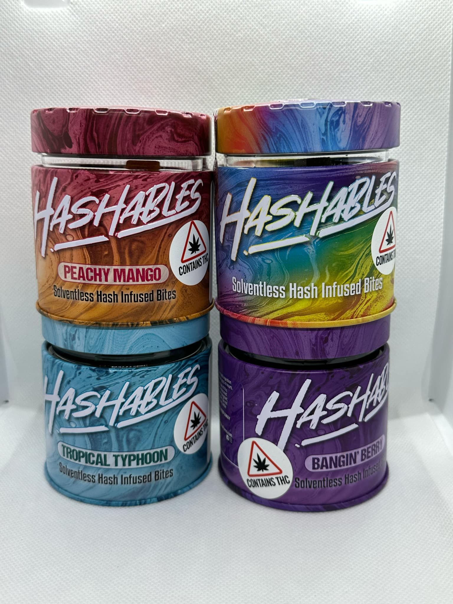 Four jars of hashables are stacked on top of each other on a table.