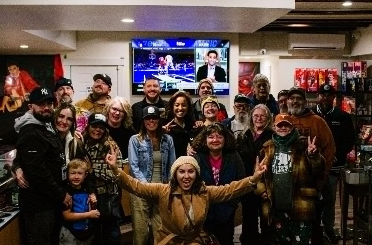 A large group of people are posing for a picture in front of a television.