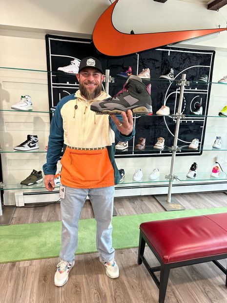 A man is standing in a shoe store holding a pair of shoes.