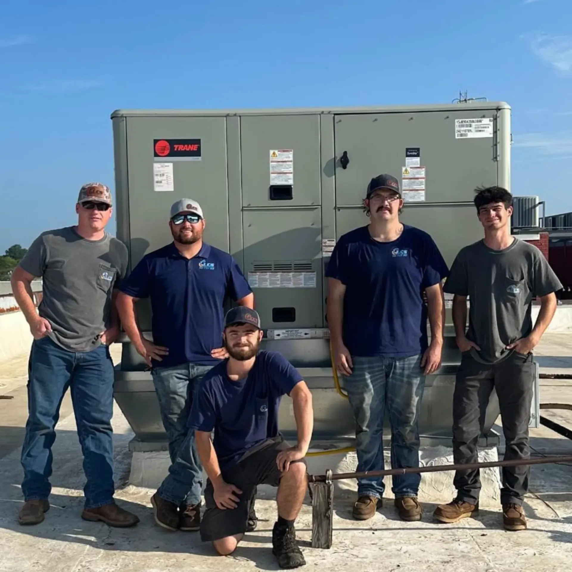 LCS Heating and Cooling - A group of men are posing for a picture in front of an air conditioner