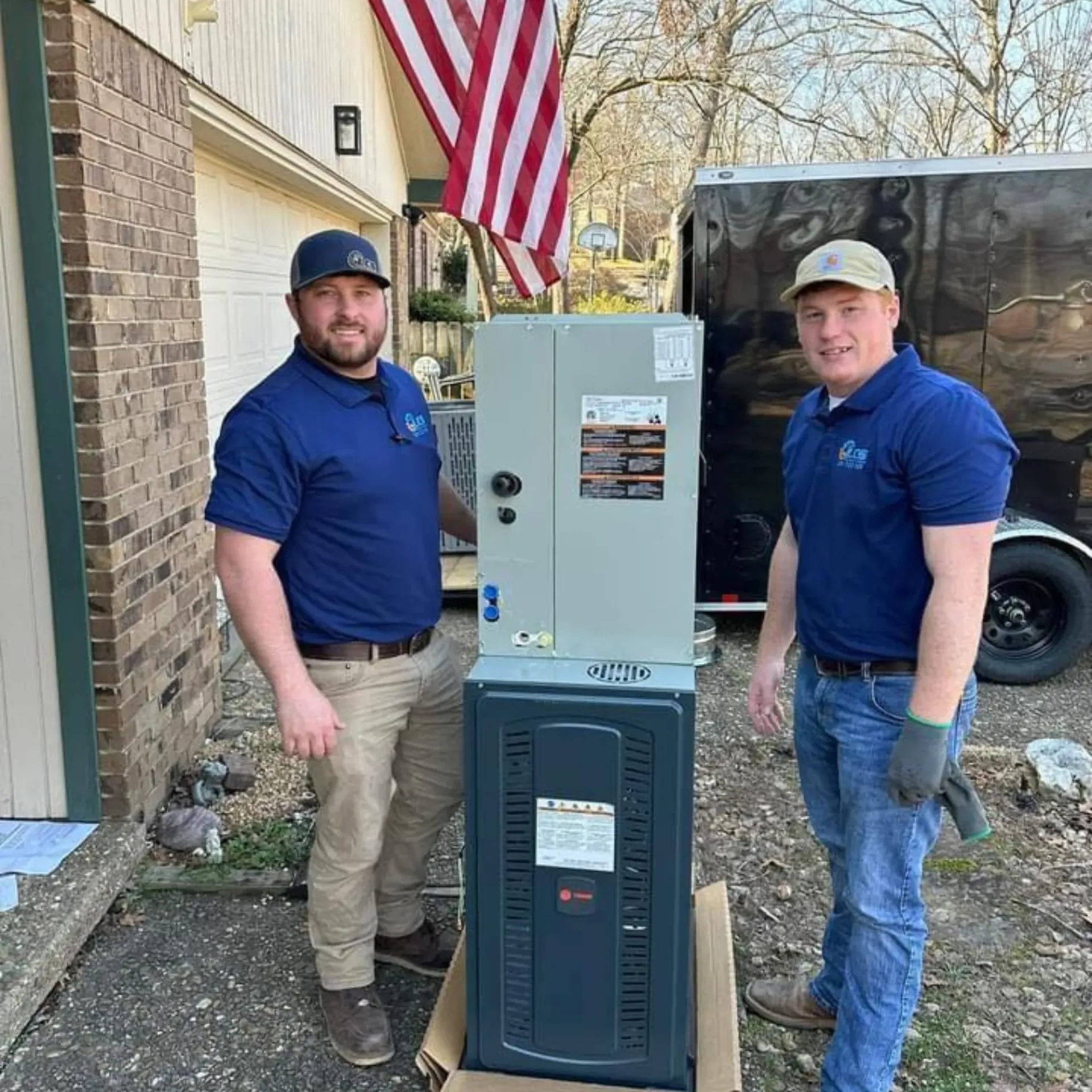 LCS Heating and Cooling - Two men are standing next to a heater in front of a house.