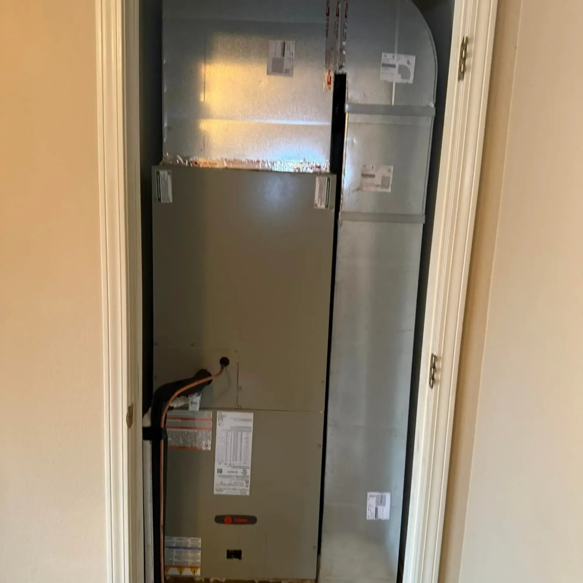 LCS Heating And Cooling - An air conditioner is sitting in a closet next to a door.