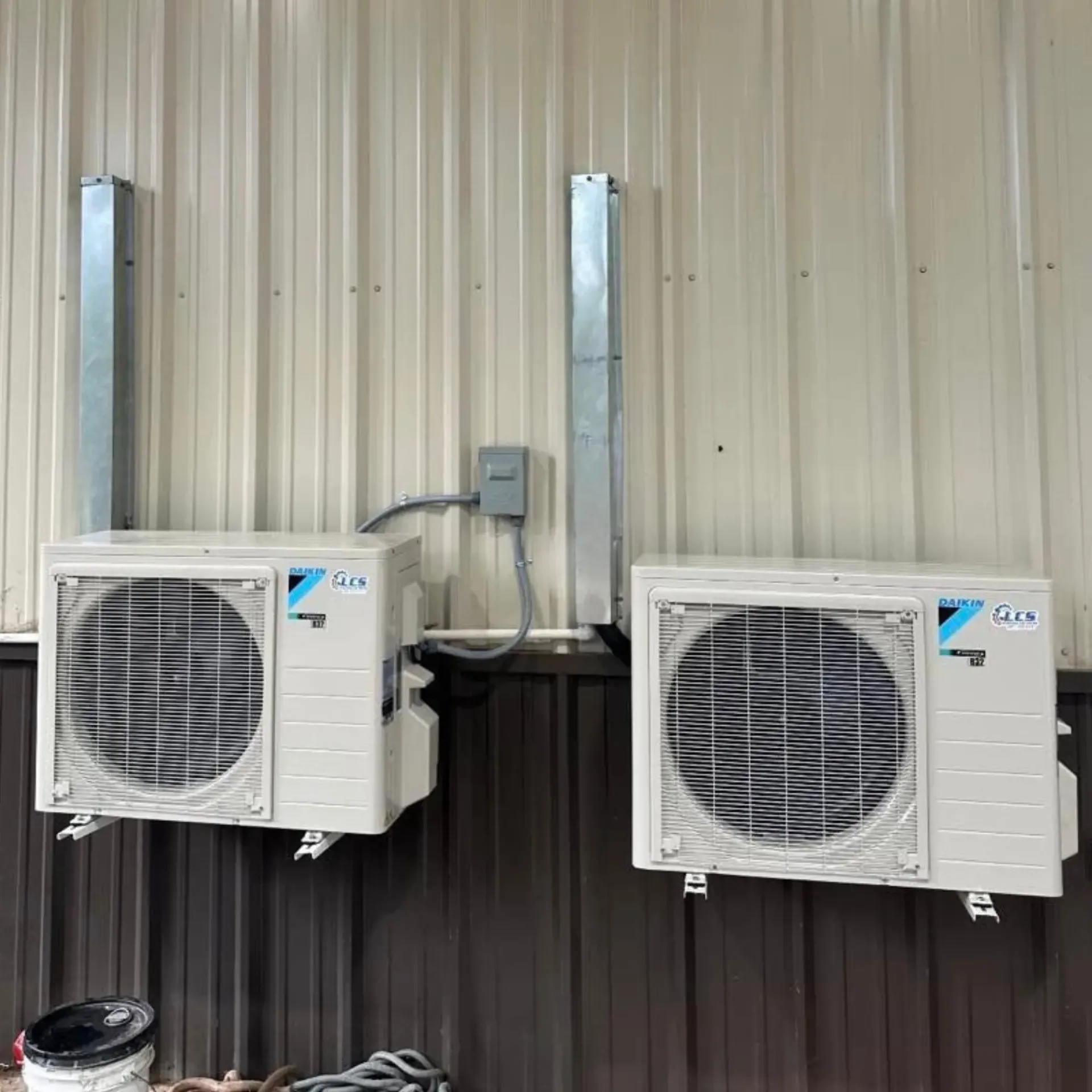 LCS Heating And Cooling - Two air conditioners are mounted on the side of a building.