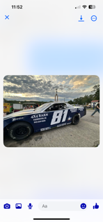 Race car, blue and black, number 81, parked on asphalt, cloudy sky.