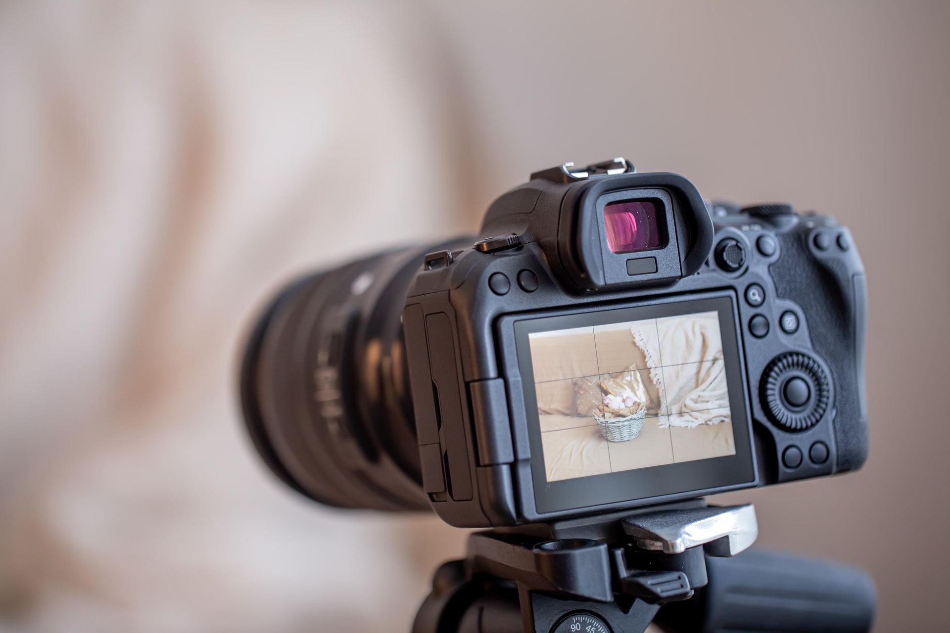 A digital camera on a tripod, displaying a picture of a kitten sitting in a basket on its rear screen.
