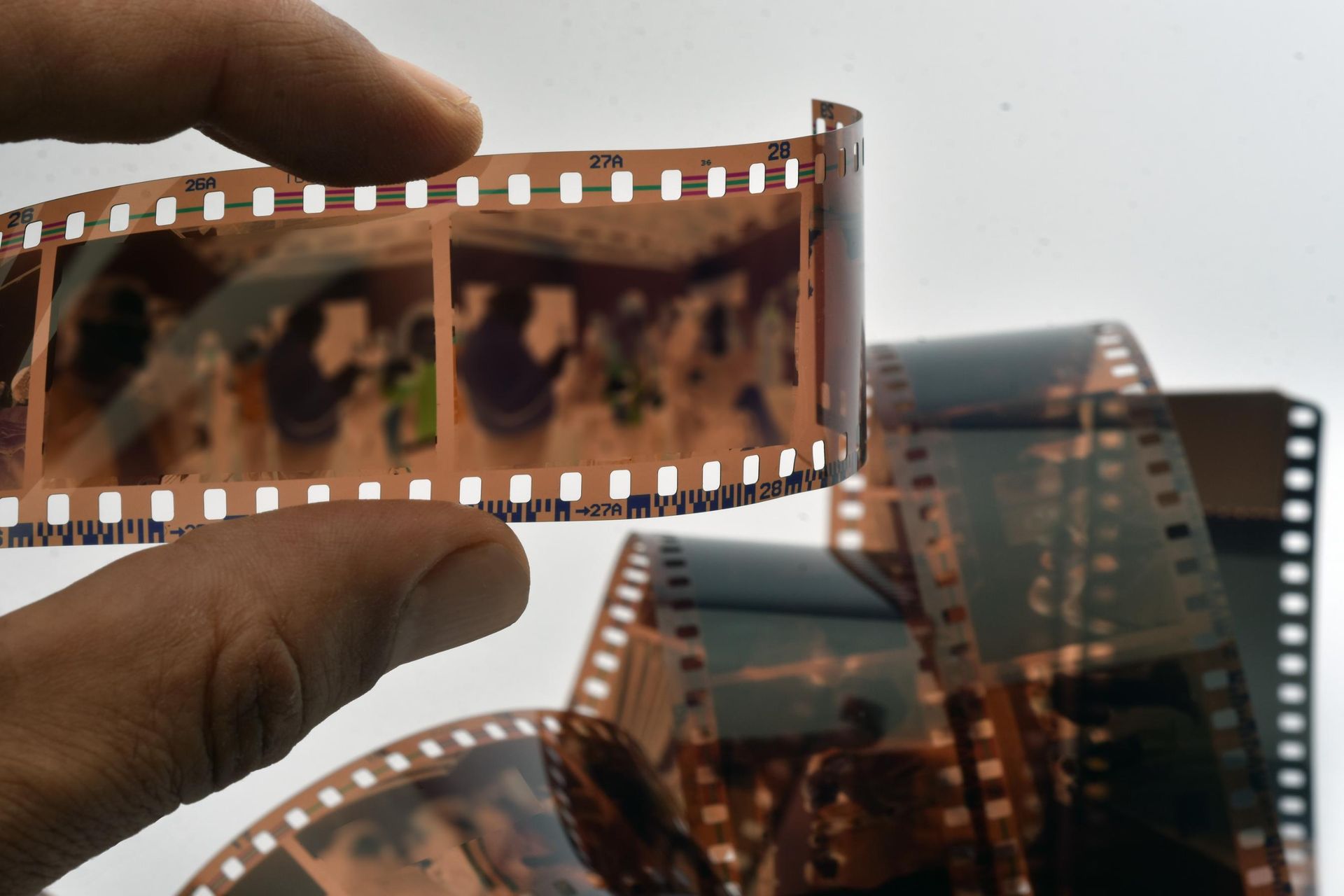 A hand holds a strip of undeveloped 35mm film negatives up to the light.