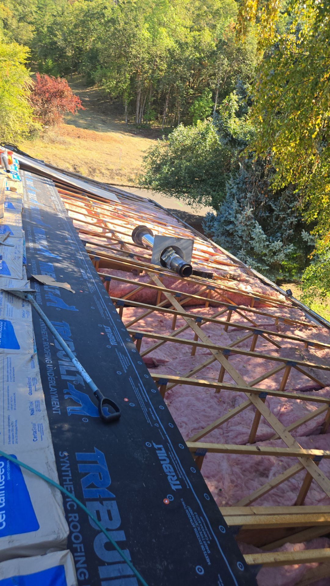Roof under construction with insulation, trusses, and roofing materials.