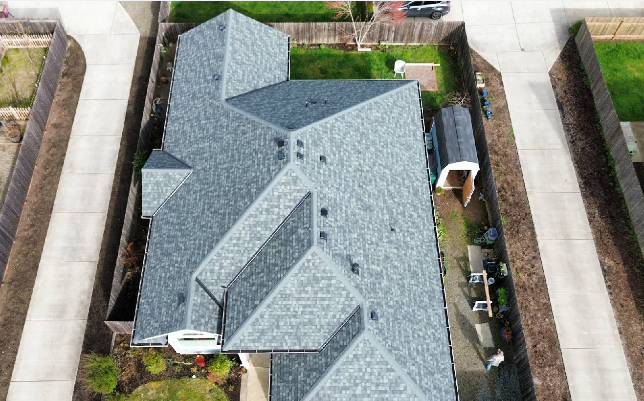 Overhead view of a house with a gray roof and concrete driveways on both sides.