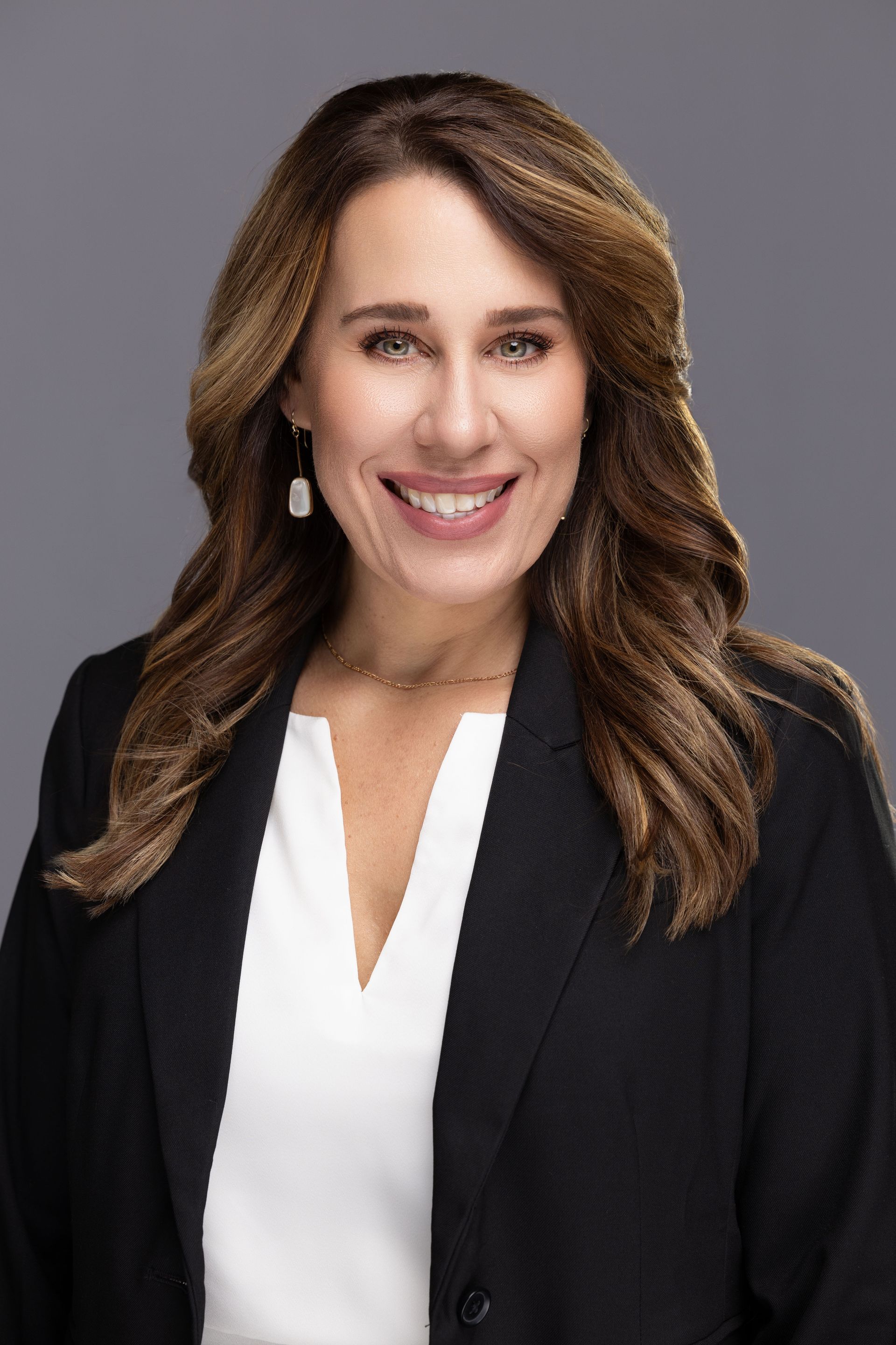 A woman wearing a black jacket and a white shirt is smiling for the camera.