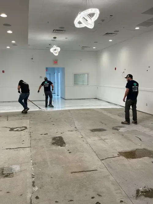 Three men are cleaning the floor of a large room.