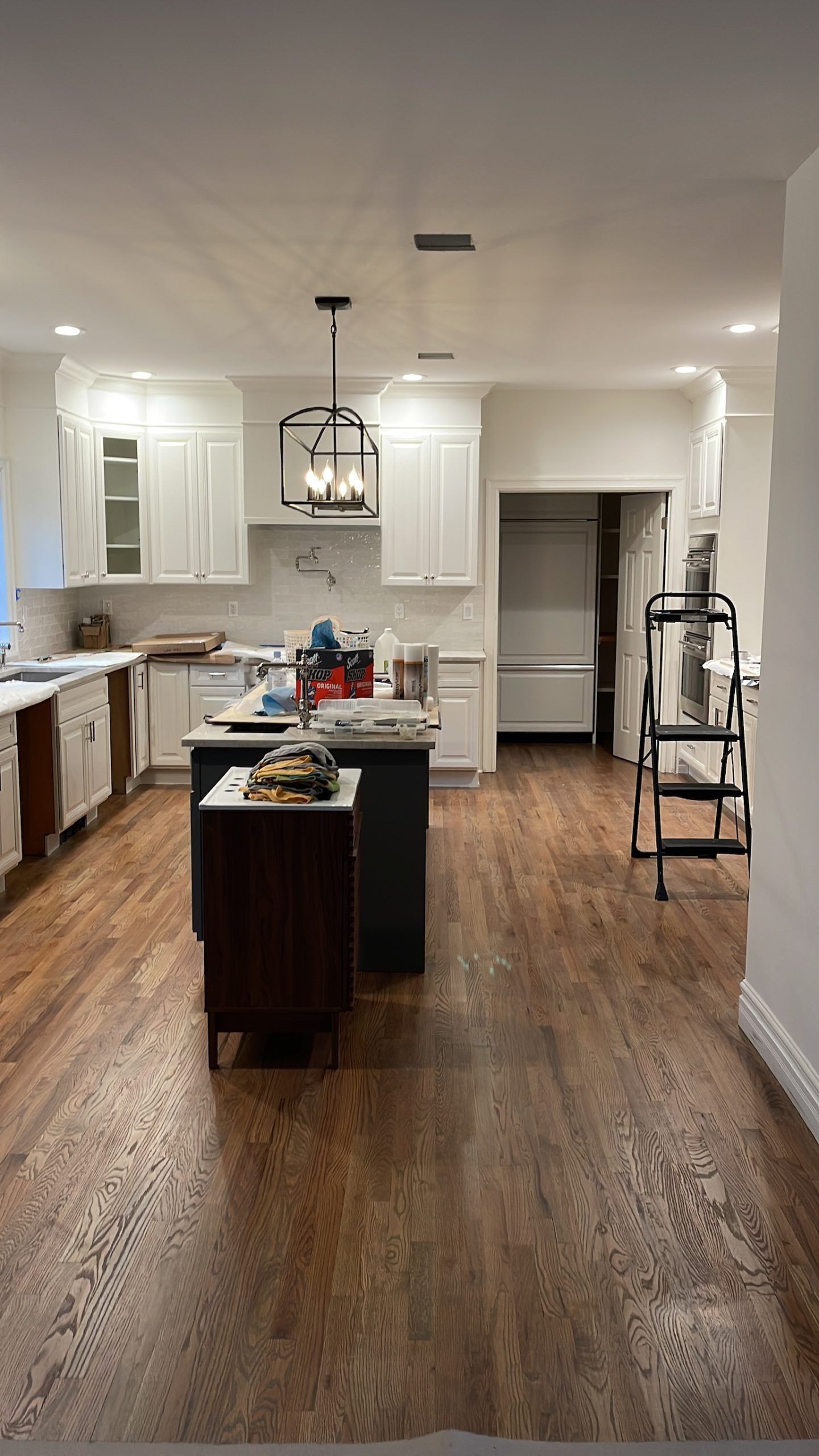 A kitchen with hardwood floors and white cabinets is being remodeled.
