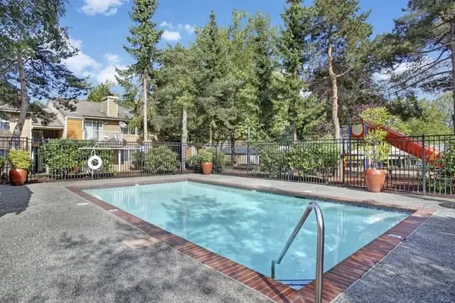 Outdoor swimming pool with lounge chairs and trees at Larch Alderwood in Lynnwood, WA.