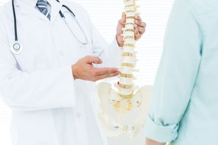 Joint Pain — Doctor Pointing Spine In Medical Office in Concord, CA