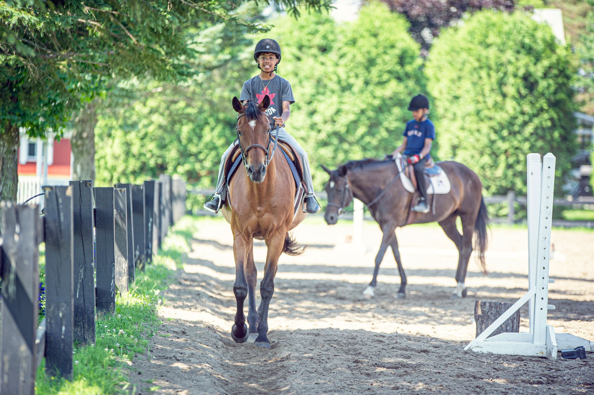 A man and a boy are riding horses in a dirt field.