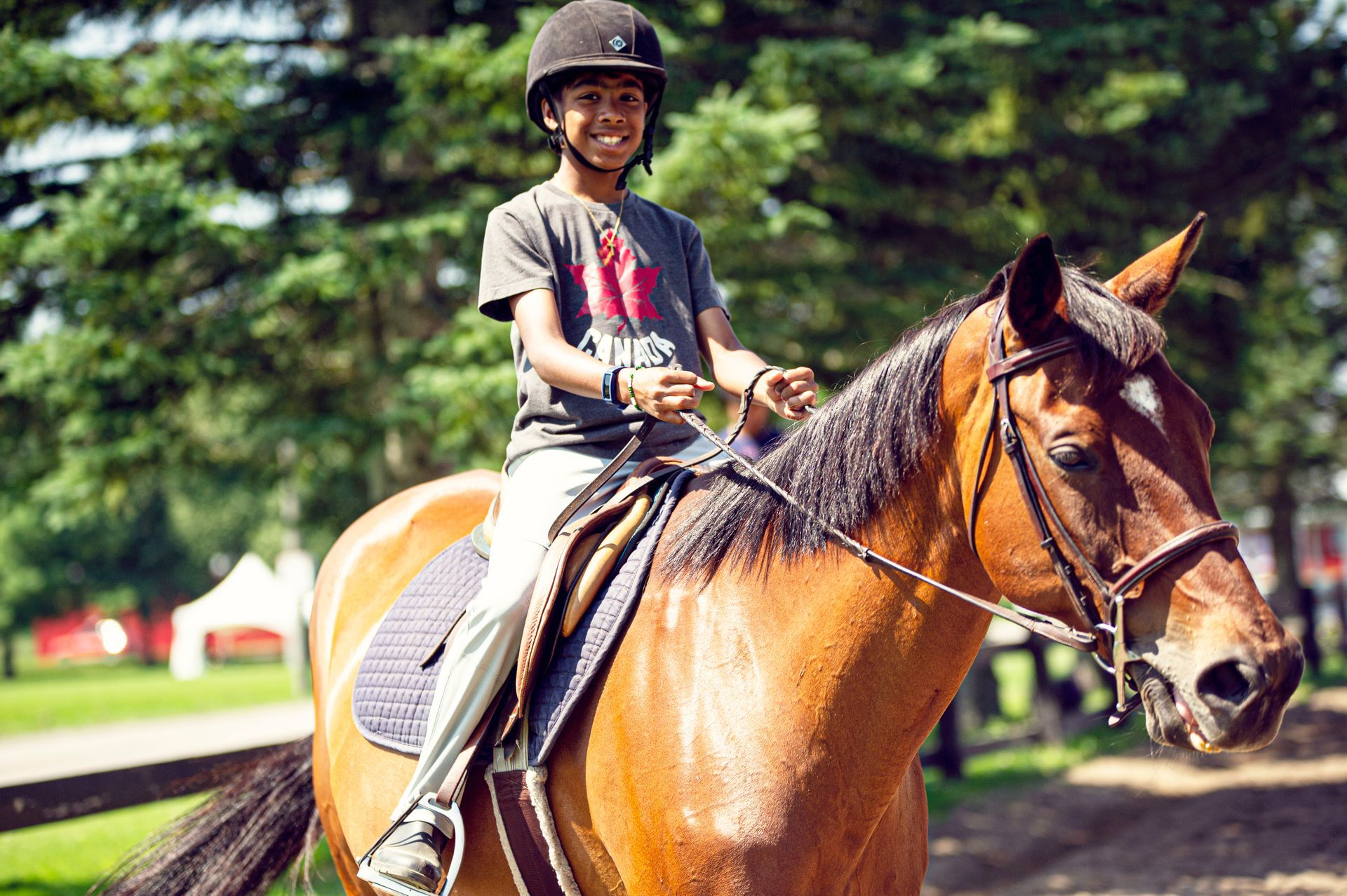 A young boy is riding a brown horse in a park.