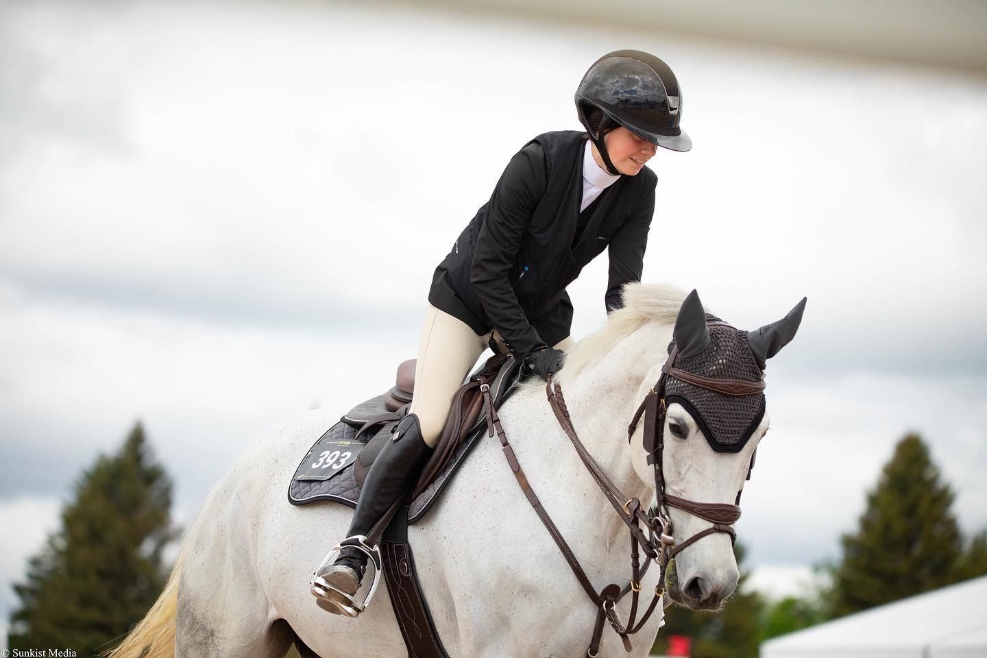 A woman is riding on the back of a white horse.