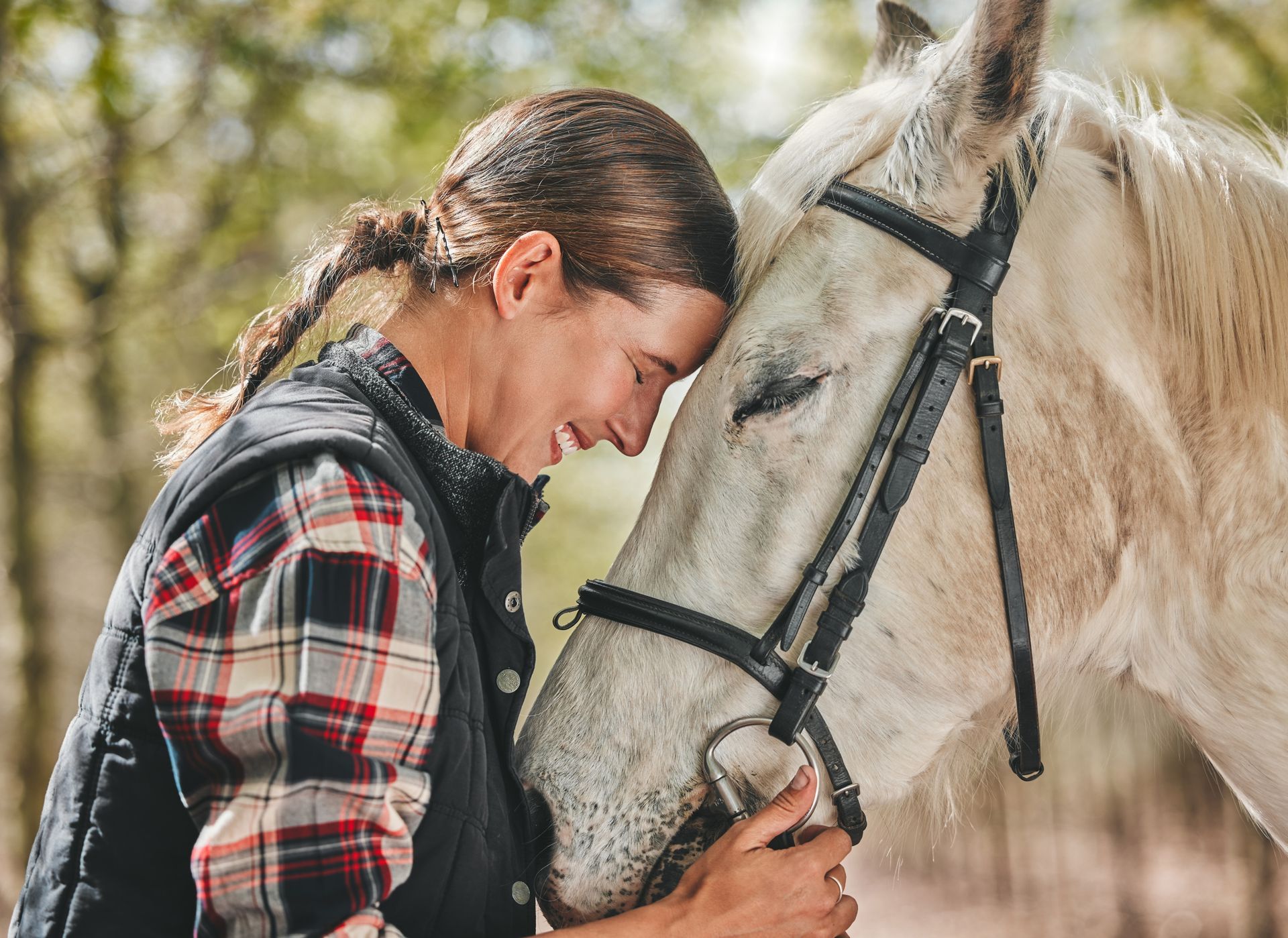 A woman is petting a white horse on the nose.