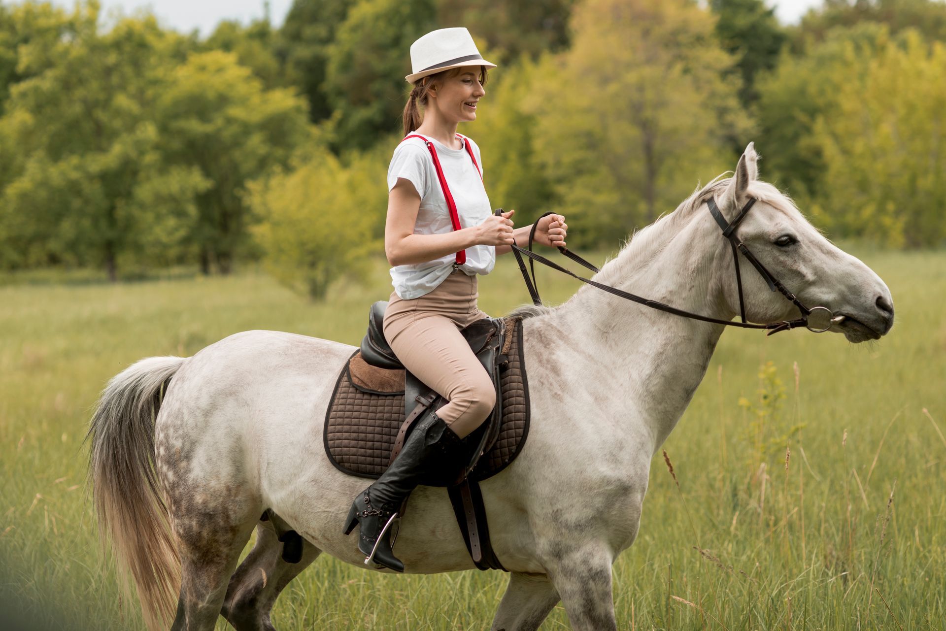 A woman is riding a white horse in a field.