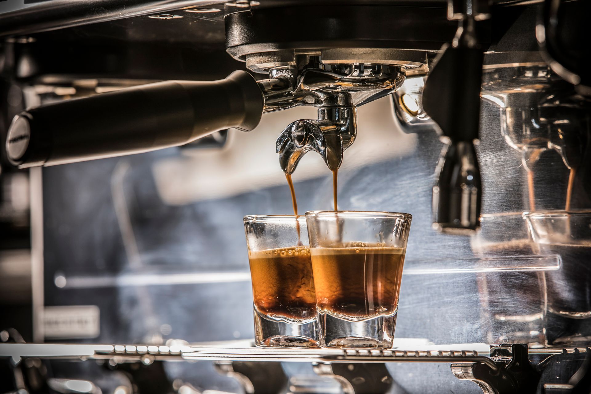 Espresso machine dispensing coffee into a white cup, blurred cafe background.