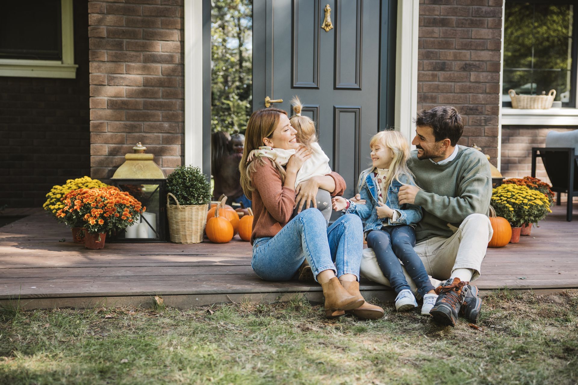 Family of four on porch steps; the children are held by their parents.