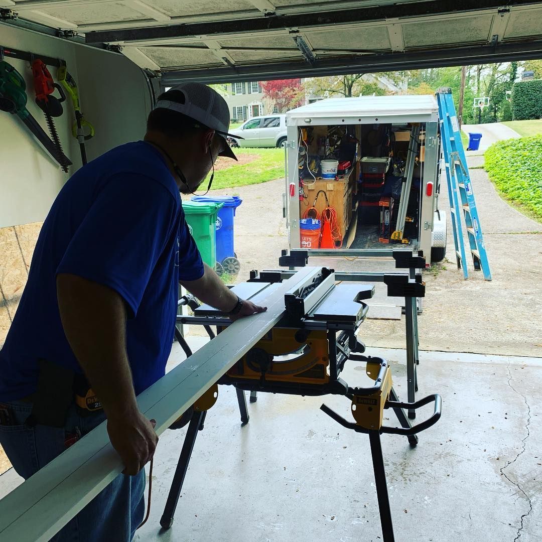 A man in a blue shirt is cutting a piece of wood