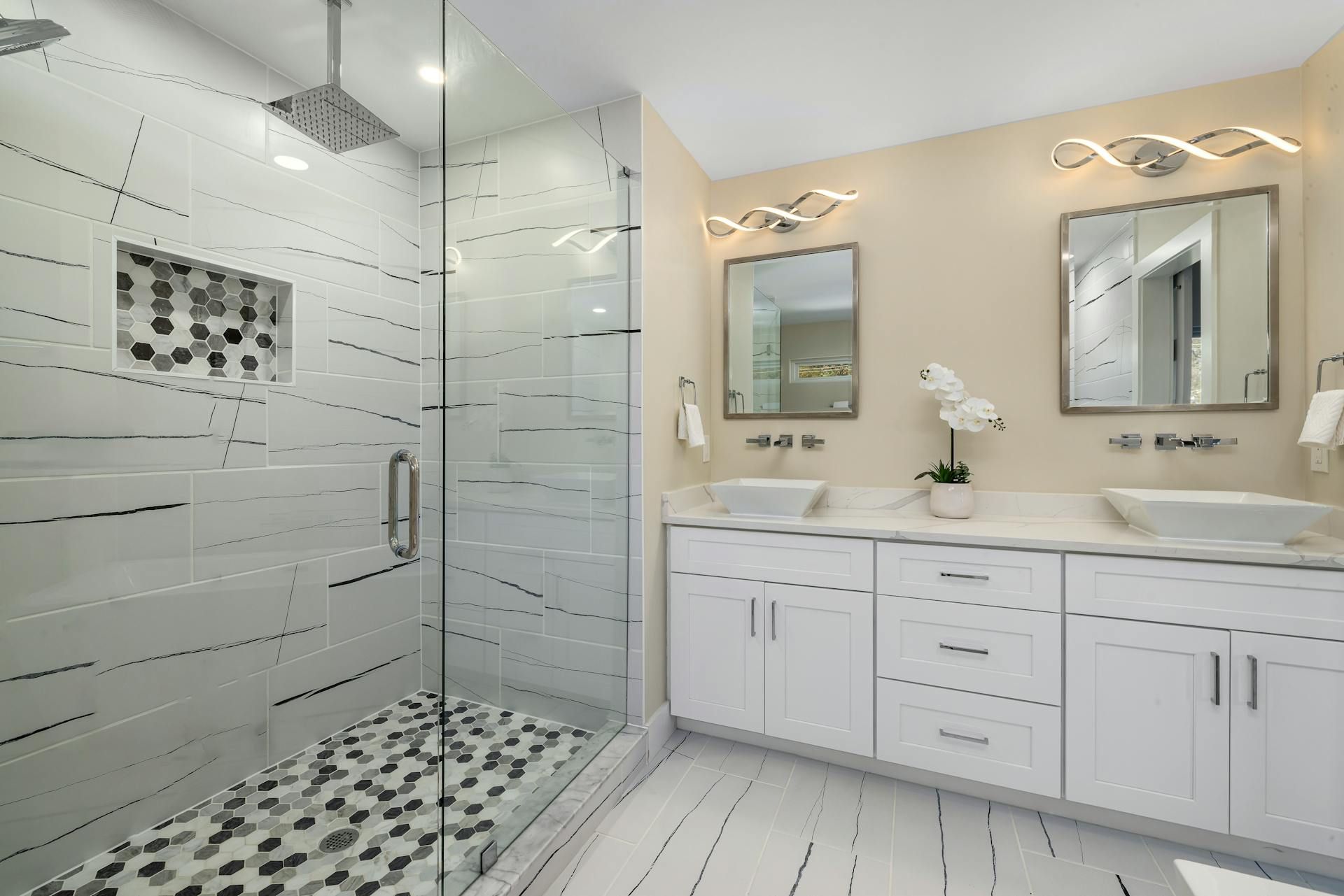 A bathroom with a walk in shower and two sinks
