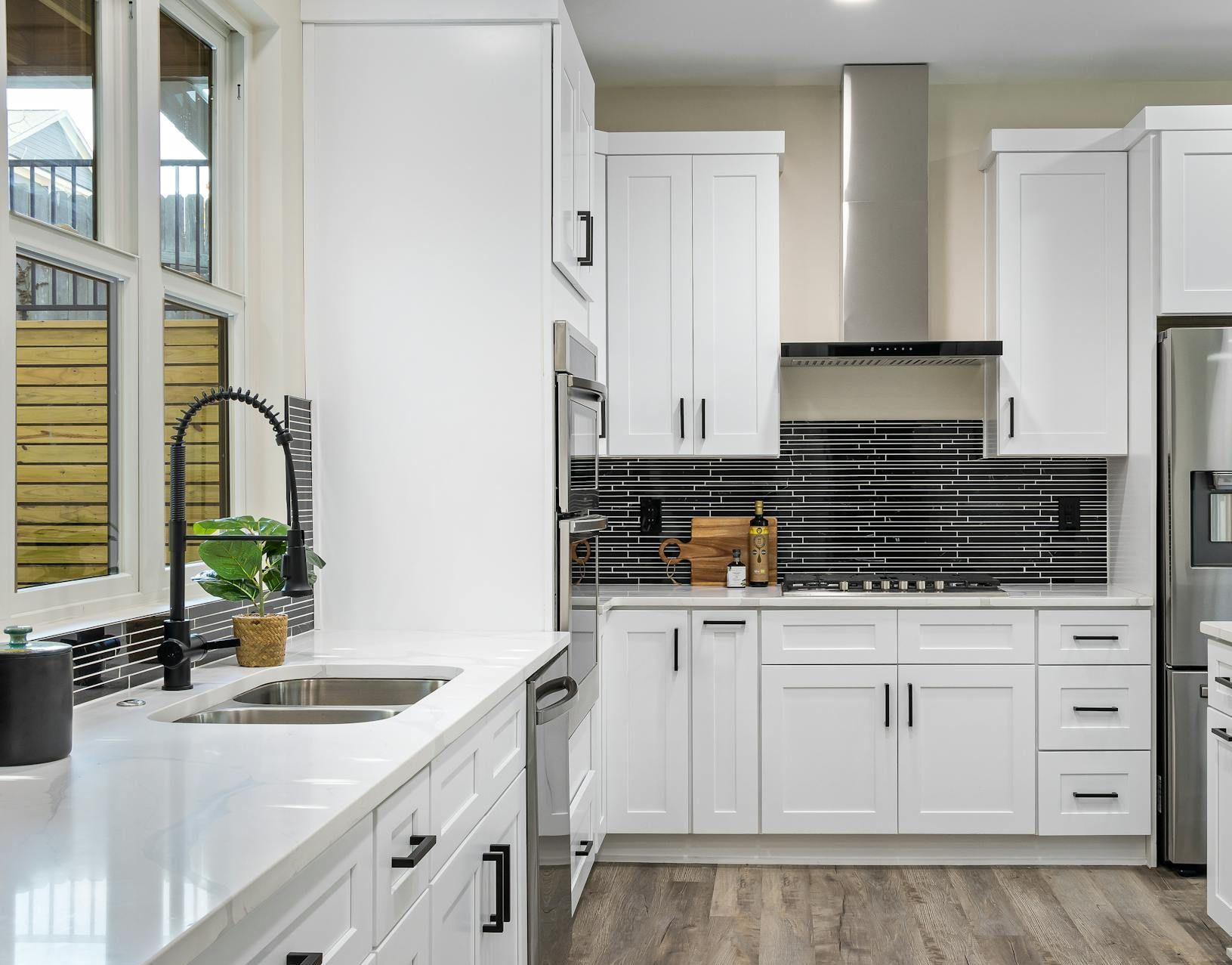 A kitchen with white cabinets , stainless steel appliances , a sink , and a refrigerator.