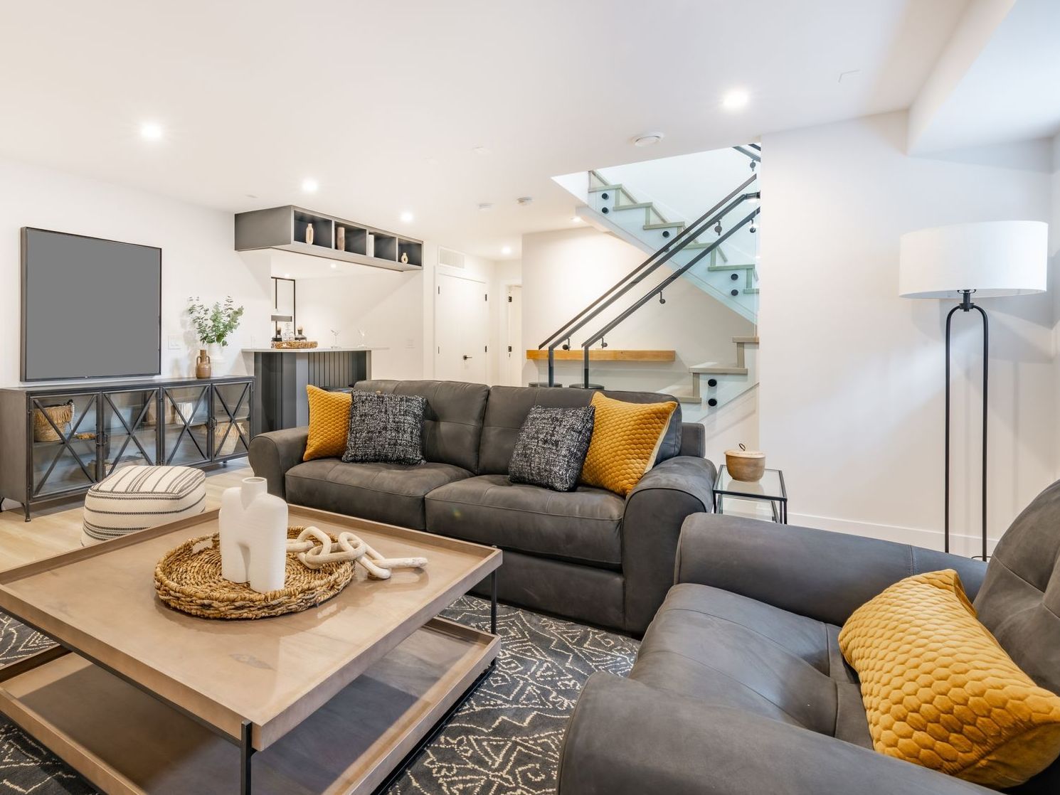 A living room with a couch , chairs , coffee table and television.