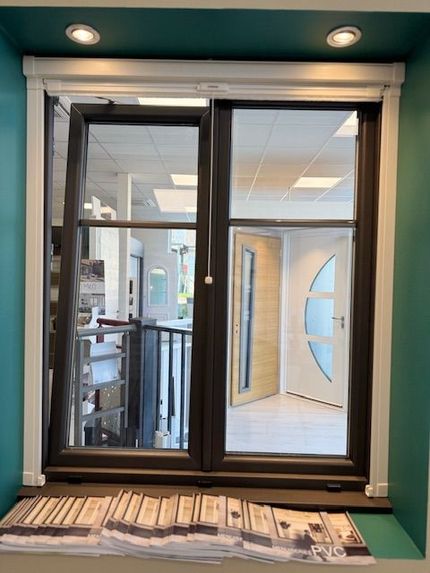 Fenêtre coulissante à cadre noir dans un couloir bleu turquoise, avec des journaux sur le rebord et une pièce lumineuse au-delà.