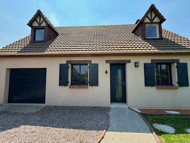 Maison de plain-pied beige avec toit de tuiles, volets foncés, garage et allée d'entrée.