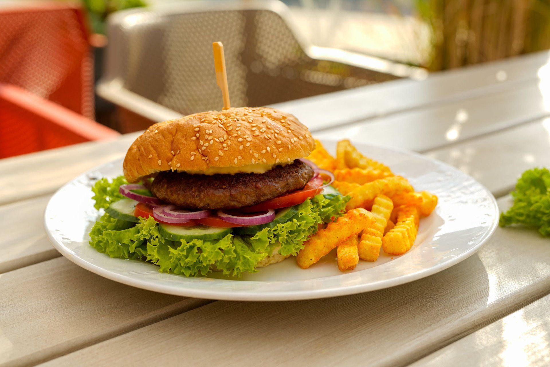Ein Hamburger und Pommes Frites auf einem weißen Teller auf einem Holztisch.