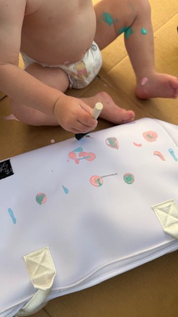 Toddler decorating a Mom’s Favorite insulated tote bag by The Stever Co. with colorful paint for a personalized keepsake gift.