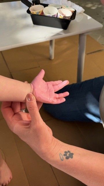 child hand covered in pink paint being prepared for handprint on The Stever Co tote bag