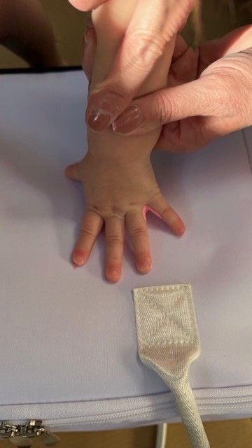 Child’s hand being pressed onto a white Mom’s Favorite insulated tote bag to create a personalized handprint keepsake gift.