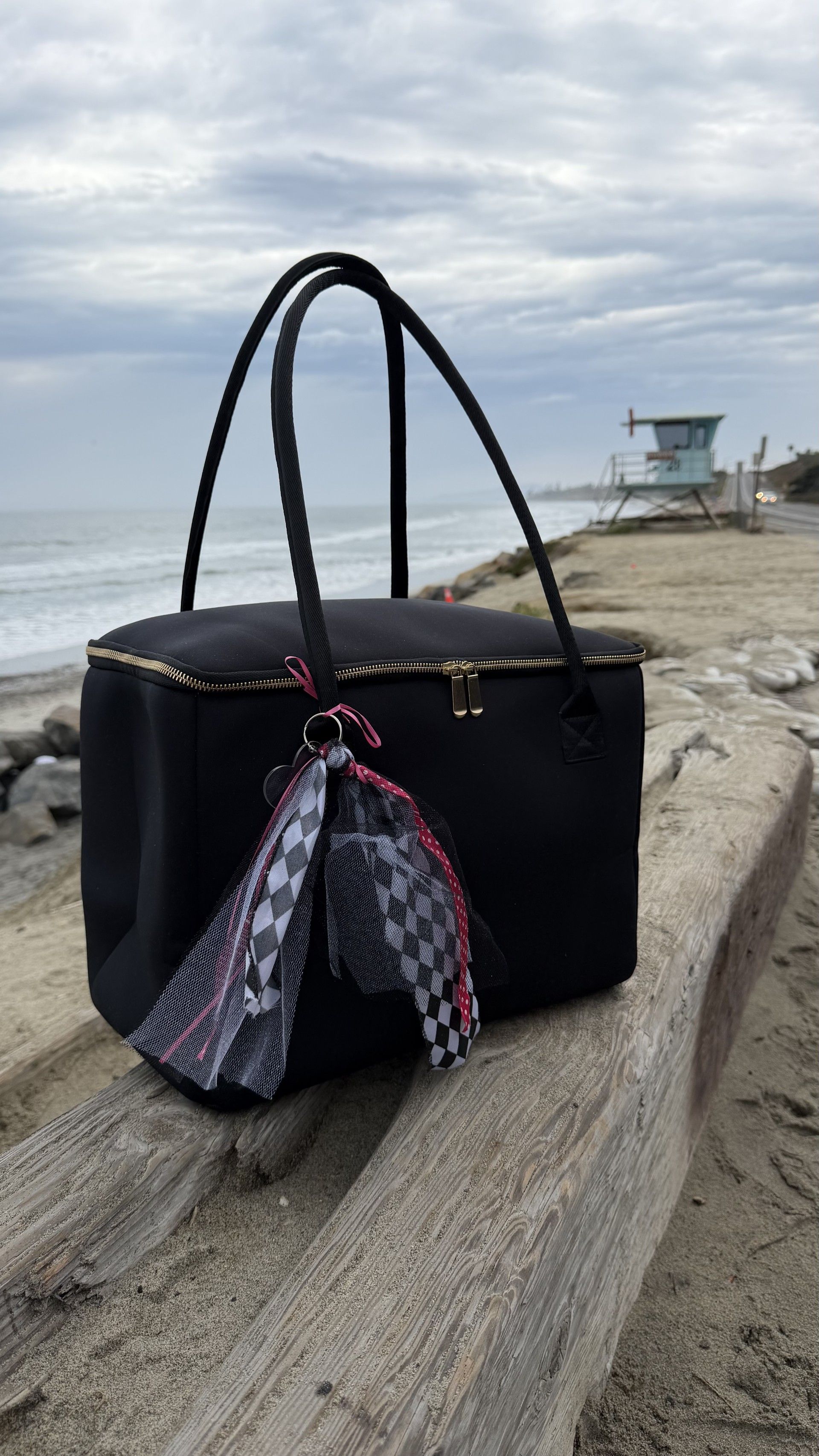 The Birdie insulated tote bag by The Stever Co with coastal lifeguard tower background